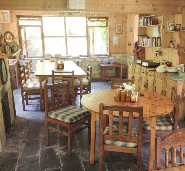 The common room — pine bookshelves, homemade preserves, and daylight through the forest